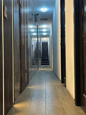 A hallway with a tiled floor, a glass door at the end, and a staircase. - Roma Nacozari Department (Aguascalientes)