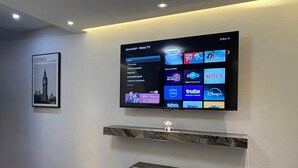 Et vægmonteret TV, der viser forskellige streamingtjenester, et indrammet billede af London og to marmorshylder.