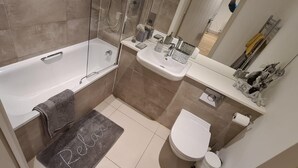 Une salle de bain comprenant une baignoire, un lavabo, des toilettes et un espace douche.