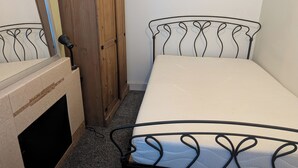 Un dormitorio con cama, armario y radiador.