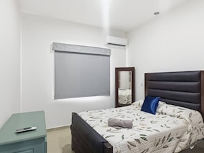 Une chambre à coucher comprenant un lit, une table de chevet, un miroir et un appareil de climatisation.