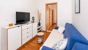 Una sala moderna con un televisor de pantalla plana, un sofá, una mesa de centro y un mueble de madera.
