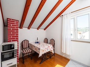 A dining area with a table, chairs, a microwave, and a brick wall. - Villa Seka Mlini (Zupa dubrovacka)