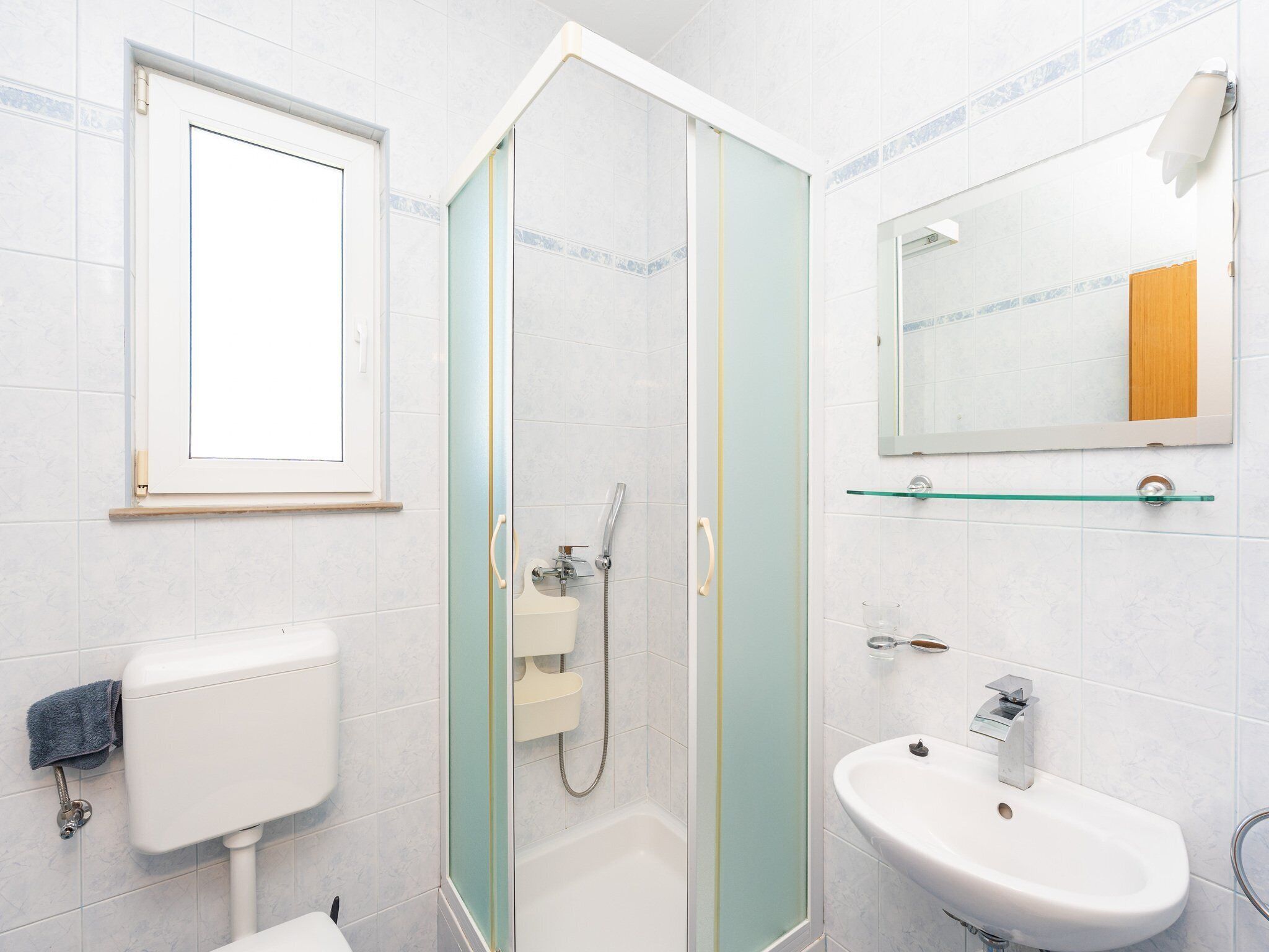 Een badkamer met toilet, wastafel, douche en spiegel.