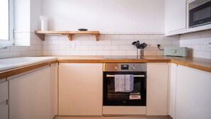 Eine Küche mit weißen Schränken, einer Holz Arbeitsplatte, einem eingebauten Ofen und einer Mikrowelle darüber.