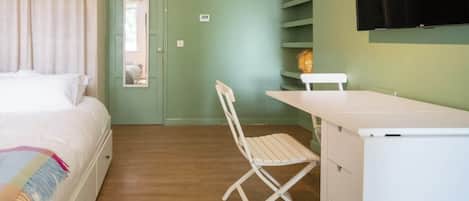 A bedroom with a bed, a desk, a chair, a television, and a wardrobe.