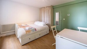Ein Schlafzimmer mit Bett, Heizkörper, Schreibtisch und Stuhl.