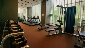 A gym with treadmills, dumbbells, and benches arranged in rows. - High Rise Luxury Stay Near Beach & Walking Street (ตำบล หนองปรือ)