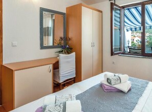 A bedroom with a bed, a desk, a wardrobe, a mirror, and a window with a view. - Villa Ivan (Rogoznica)