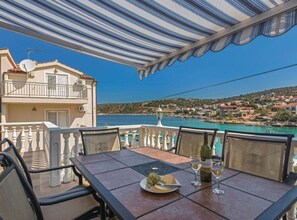 A terrace with a table set for dining, overlooking a coastal town. - Villa Ivan (Rogoznica)