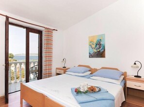 Une chambre à coucher avec un lit, une table de chevet, une lampe, un tableau et un balcon avec vue.