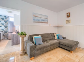 Ein Wohnzimmer mit Ecksofa, Blumentopf und einem Bild an der Wand.