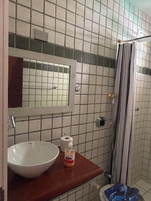 Un baño con lavamanos blanco, espejo, cortina de ducha y retrete.