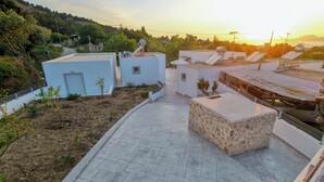 Eine Dachterrasse mit befestigtem Boden, Satellitenschüsseln und einem kleinen Gartenbereich.