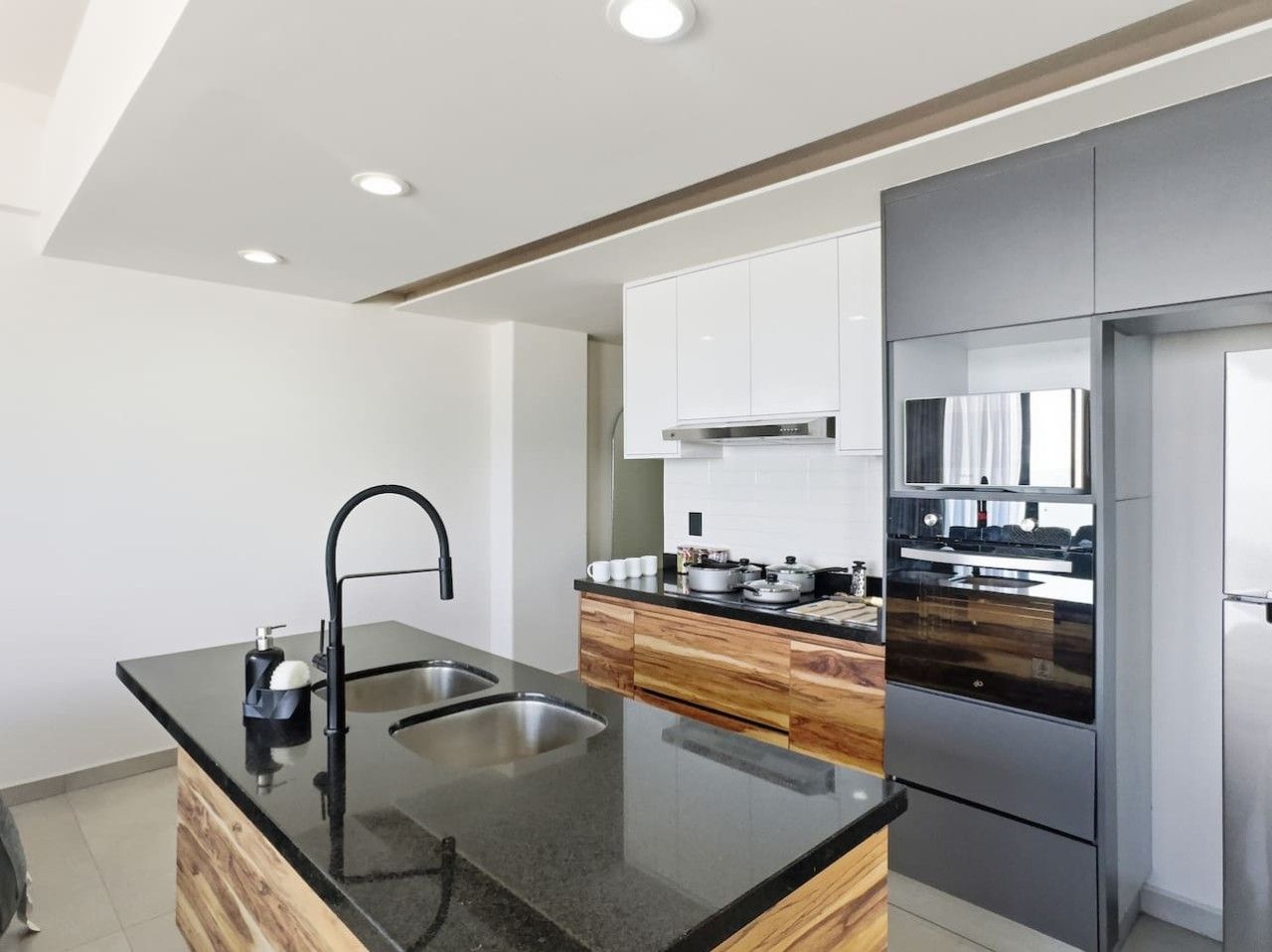 A modern kitchen with a black countertop, stainless steel sink, and built-in appliances.