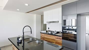 A modern kitchen with a black countertop, stainless steel sink, and built-in appliances.
