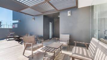 Une terrasse sur le toit aménagée avec des meubles en osier, une paroi en verre et un design moderne au niveau du plafond.