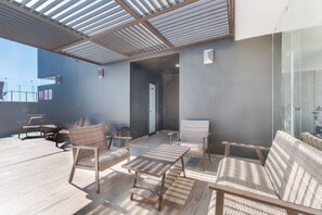 Eine Dachterrasse mit Korbmöbeln, einer Glaswand und einem modernen Deckenstil.