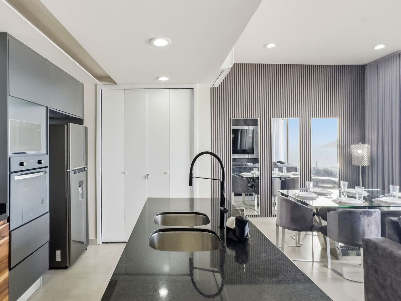 A modern kitchen with a central island, built-in appliances, and a dining area with a view.