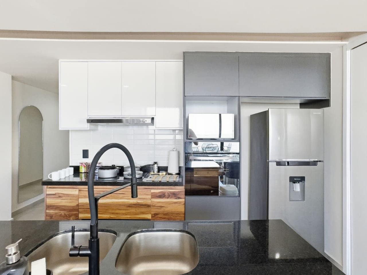 A modern kitchen with stainless steel appliances, a black faucet, and a wooden countertop backsplash.