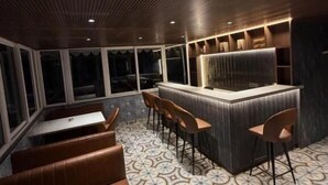 Ein Restaurant mit Holzbalkendecke, gemustertem Boden, einer Bar und Sitzgelegenheiten.