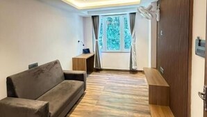 Ein modernes Zimmer mit Holzboden, einer Couch, einer Bank, einem Schreibtisch und einem Vorhangfenster.