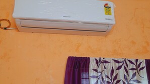 Un condizionatore d'aria montato su una parete con una tenda viola e bianca sottostante.