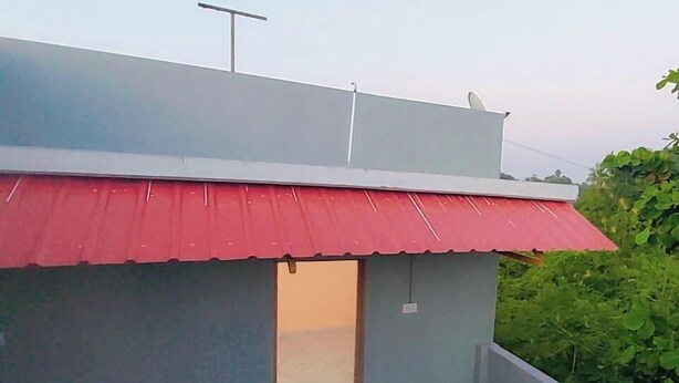 Un edificio con un tendone rosso, un piccolo portone e un'antenna parabolica sul tetto.