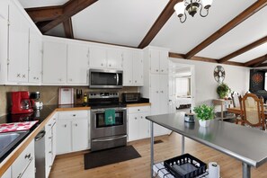A modern kitchen with white cabinets, stainless steel appliances, and a wooden ceiling.