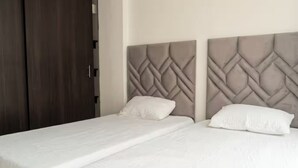 Un letto matrimoniale con testiera decorata da un motivo geometrico, un'armadio in legno e una parete liscia.