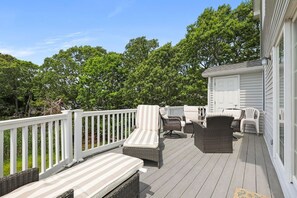 Eine überdachte Terrasse mit Korbmöbeln und einem weißen Geländer.