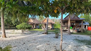 A beachside resort with thatched-roof cottages, a sandy beach, and a small pool area.