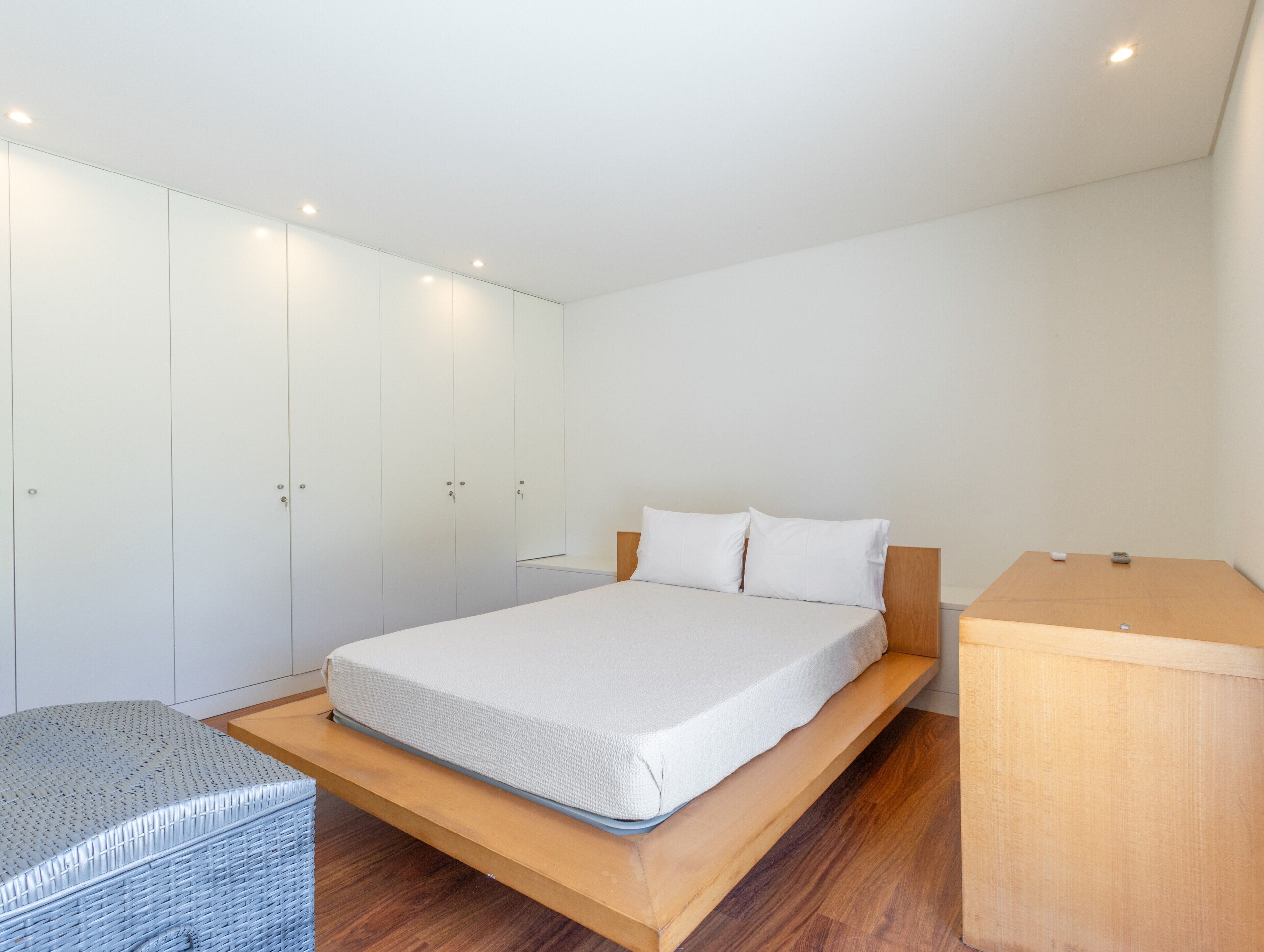 A bedroom with a bed, a wardrobe, and a small wooden table.