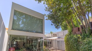 Un edificio moderno con amplios ventanales, terraza exterior y un jardín cuidado.
