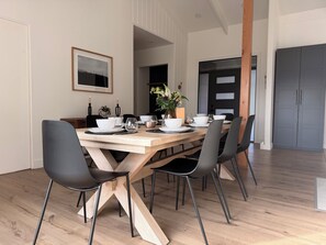 A dining area with a wooden table, black chairs, and a framed picture on the wall.