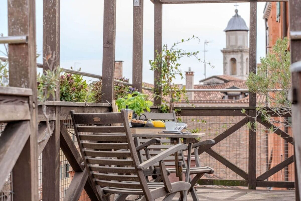 A wooden deck with a table and chairs, a laptop, and a yellow fruit.