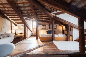 Ein Schlafzimmer im Dachgeschoss mit freiliegenden Holzbalken, einem Bett, einem Schreibtisch und einem Stuhl.