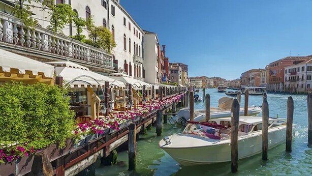 Ein Restaurant am Kanal mit Außenbereich, ein Boot liegt in der Nähe, und Gebäude säumen das Wasser.