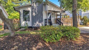 A single-story house with a covered porch, a visible staircase, and a fenced yard. - The Good Life OKI | Hot Tub & Game Room (Oak Island)