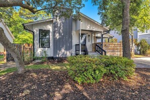 A single-story house with a covered porch, a visible staircase, and a fenced yard. - The Good Life OKI | Hot Tub & Game Room (Oak Island)
