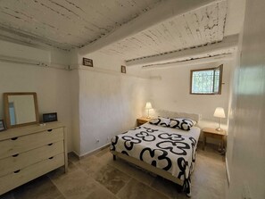 Une chambre à coucher comprenant un lit, deux tables de chevet, une commode, une fenêtre et un miroir.