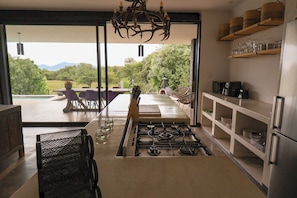 A modern kitchen with a gas stove, open shelving, and a view of an outdoor dining area.
