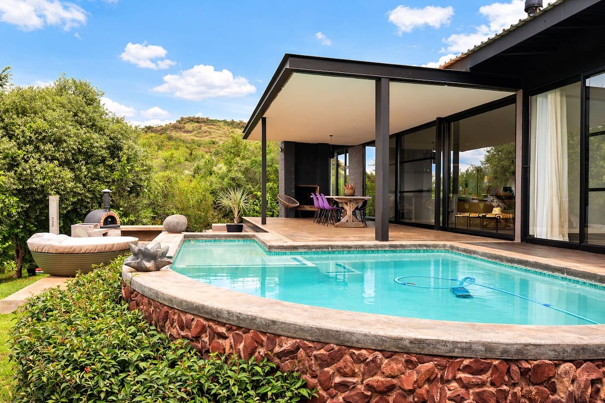 A modern house with a swimming pool, outdoor seating, and a barbecue area.