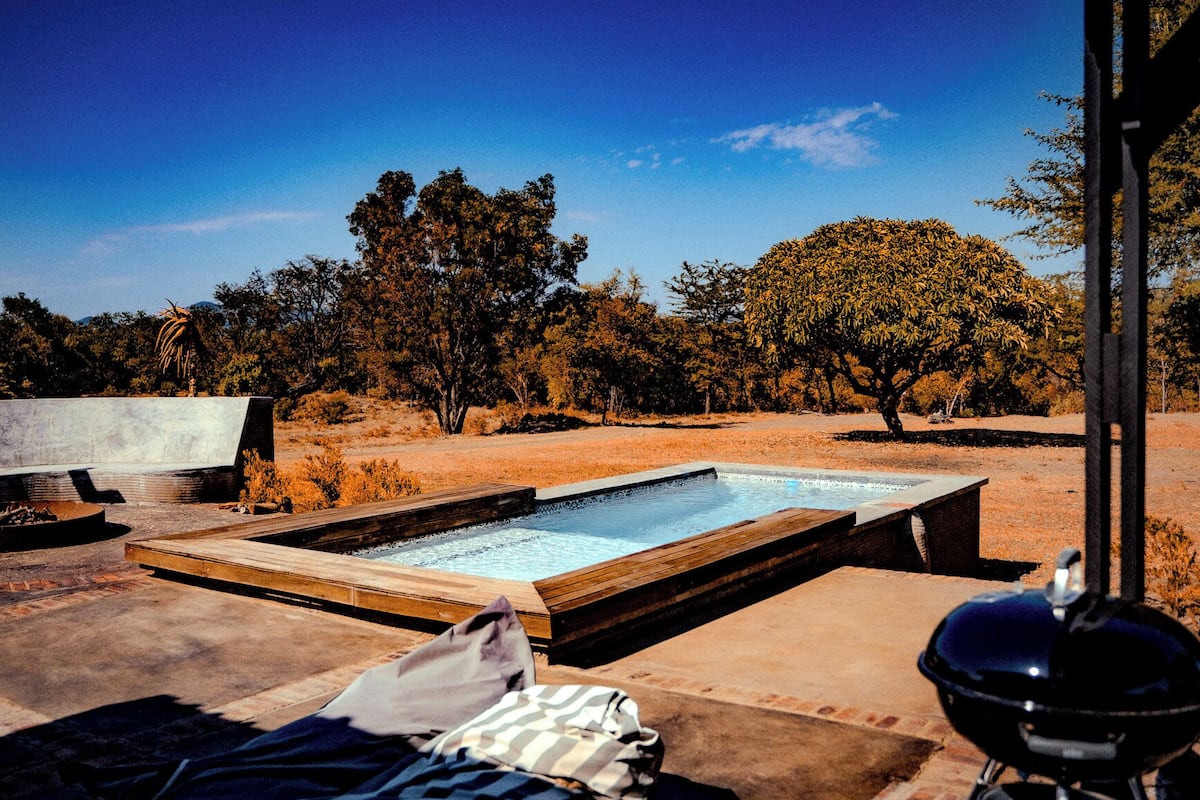 A pool area with two hot tubs, a barbecue grill, and a fire pit.