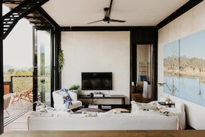 Un salon moderne avec un téléviseur à écran plat, un canapé, une table basse et un tableau accroché au mur.