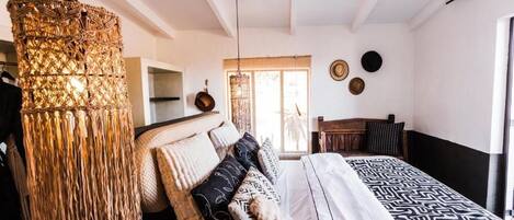 Un dormitorio con cama, lámpara colgante, ventilador de techo y ventana.