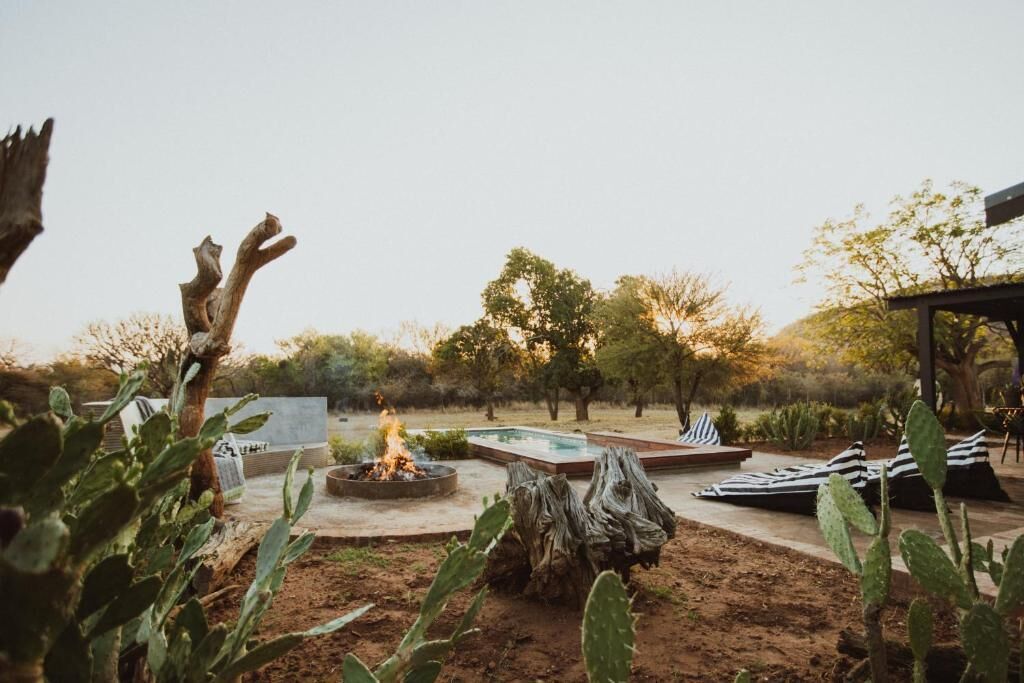 An outdoor area with a fire pit, seating, and a pool.