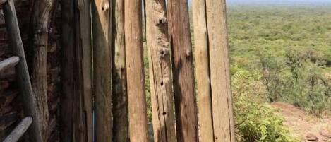 A rustic wooden fence with a stone wall, a ladder, and a clear view of a hilly landscape.
