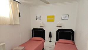 Une chambre double avec deux lits, une table de chevet, une lampe et des œuvres d’art murales.