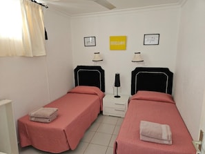 Ein Doppelzimmer mit zwei Betten, einem Nachttisch, einer Lampe und Wandbildern.